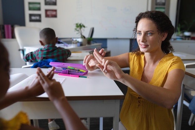 Foto een jonge blanke lerares die met een afro-amerikaans meisje praat in gebarentaal.
