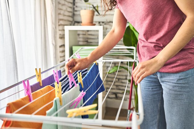 Een jonge blanke vrouw die kleren ophangt aan een waslijn in fro