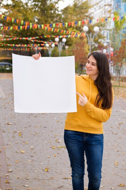 Een jonge blanke vrouw wijst met haar vinger naar een blanco vel papier en glimlacht