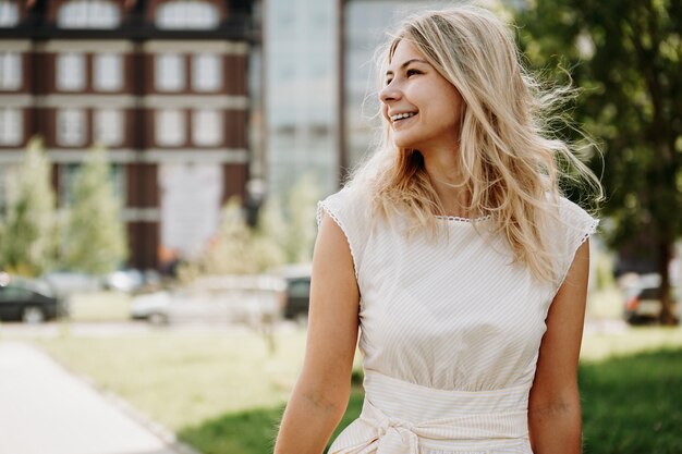 Een jonge blonde in een witte jurk op de achtergrond van een Europese stad. Het concept van levensstijl en geluk