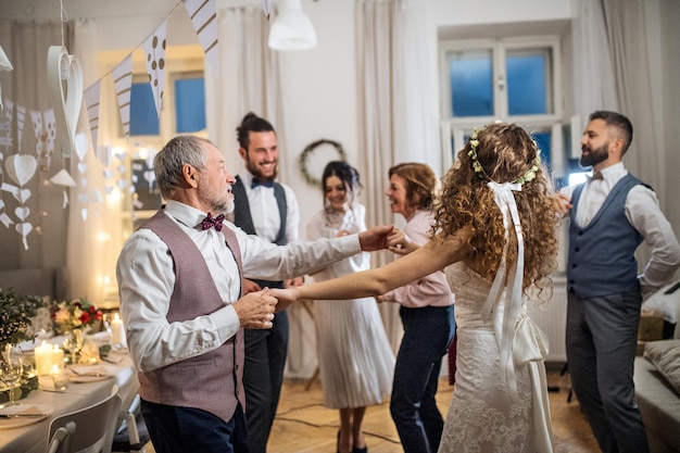 Een jonge bruid die met grootvader en andere gasten op een bruiloftsreceptie danst