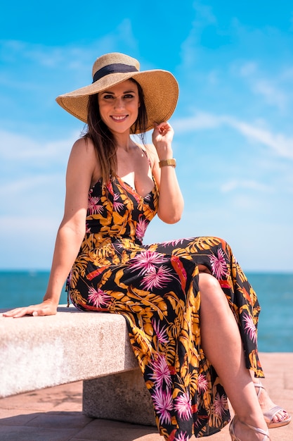 Een jonge brunette in een strooien hoed aan zee