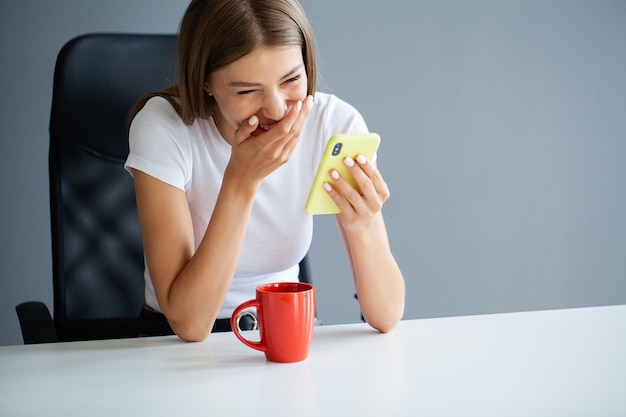 Een jonge brunette vrouw kijkt naar het scherm van de mobiele telefoon