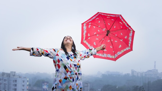 Een jonge dame die een paraplu vasthoudt en geniet van het regenachtige weer tijdens het moessonseizoen in India