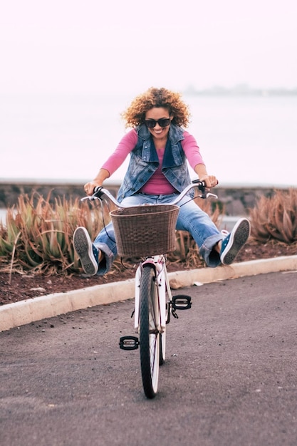 Een jonge dame fietsen alleen op straat met uitzicht op de kust van de oceaan Buitenlucht vrijetijdsactiviteit groen transport vrouw Mensen en gezonde levensstijl Concept van toerist op vakantie plezier