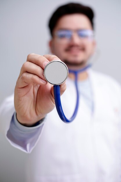 Foto een jonge dokter staat en houdt een stethoscoop in de hand en glimlacht