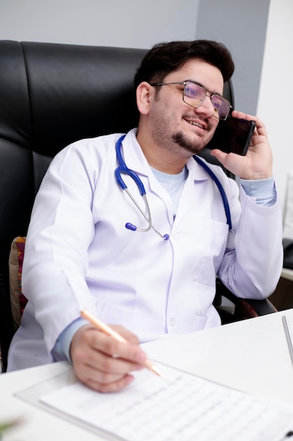 Foto een jonge dokter zit in de kliniek en praat op mobiele telefoon