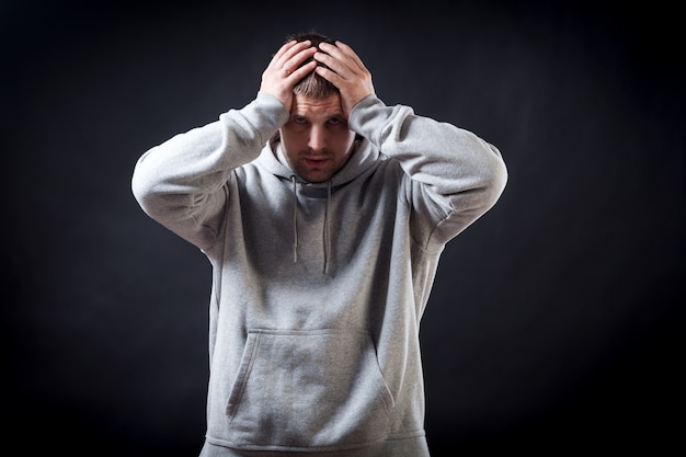 Een jonge donkerharige man in een sportief grijs sweatshirt was boos dat hij ziek werd van een verkoudheid