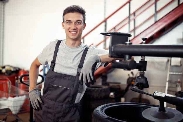 Een jonge en gekwalificeerde automonteur lacht terwijl hij aan het werk is tijdens een korte pauze.