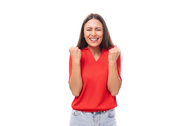 Een jonge Europese vrouw met donker steil haar, gekleed in een rood shirt met korte mouwen, gebaart actief