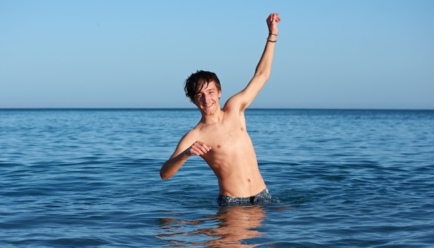 Een jonge, fitte blanke man die poseert en plezier heeft in de zee