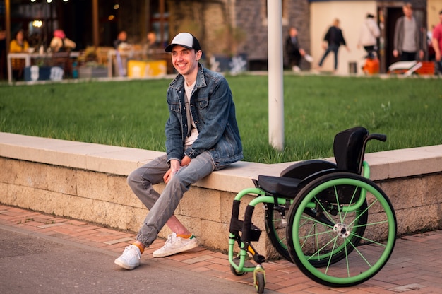 Een jonge gehandicapte man zit naast een rolstoel en toont haar de middelvinger van hoge kwaliteit foto