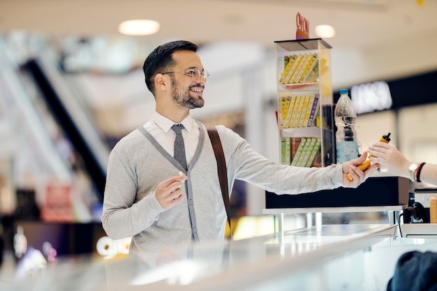 Een jonge gelukkige man koopt een vaperizer in een winkelcentrum