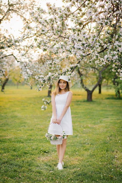 Een jonge gelukkige vrouw loopt door een appelboomgaard tussen witte lentebloemen