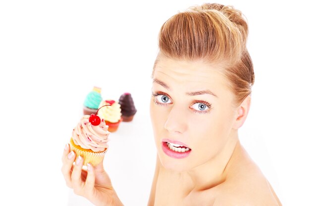 Foto een jonge gelukkige vrouw poseren met een cupcake op een witte achtergrond over