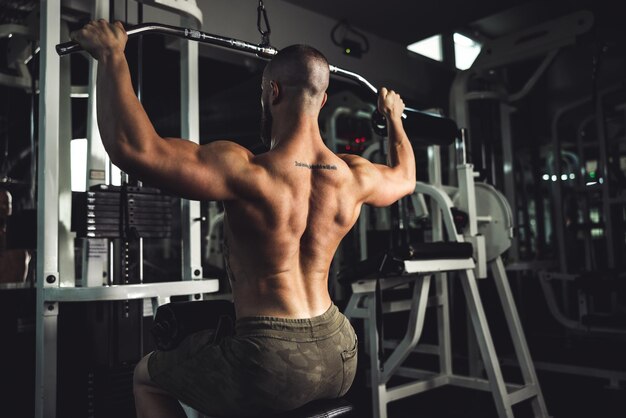 Een jonge gespierde bodybuilder die hard traint voor zijn rugspieren in de sportschool.