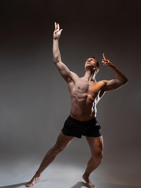 Een jonge gespierde man in een expressieve pose, mooie spieren, buitengewoon atletisch lichaamsportret op...