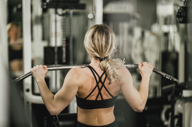 Een jonge gespierde vrouw doet training op een machine in de sportschool.