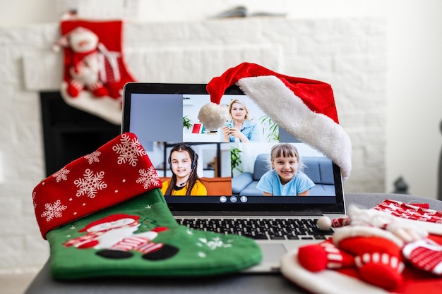 Een jonge glimlachende vrouw die rode Kerstmanhoed draagt die videogesprek voert op sociaal netwerk met familie en vrienden op eerste kerstdag.