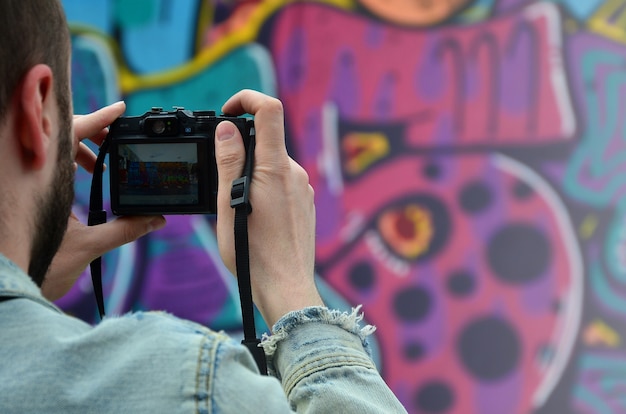 Een jonge graffitikunstenaar fotografeert zijn voltooide foto