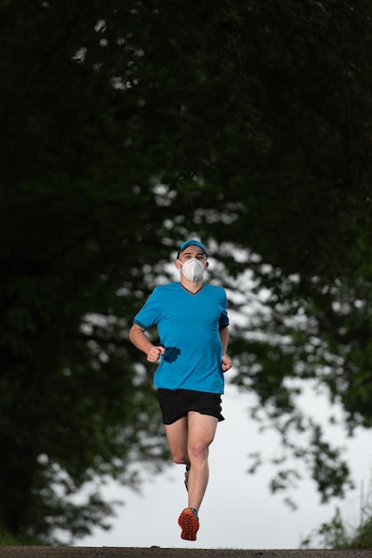 Een jonge hardloper die traint met een medisch gezichtsmasker tijdens de coronavirus-pandemie covid19