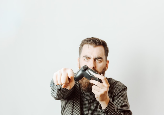 Foto een jonge hipster-man met een witte achtergrond die een consolestootkussen vasthoudt terwijl hij boos iets signaleert