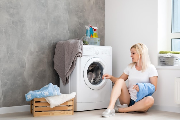 Een jonge huisvrouw met wasmachine en kleding. wasdag.