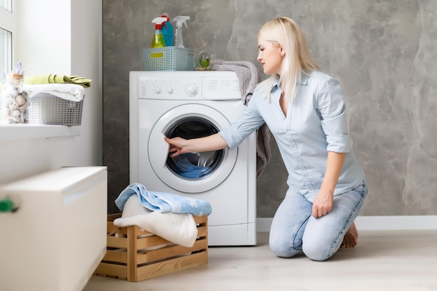 Een jonge huisvrouw met wasmachine en kleding. Wasdag.