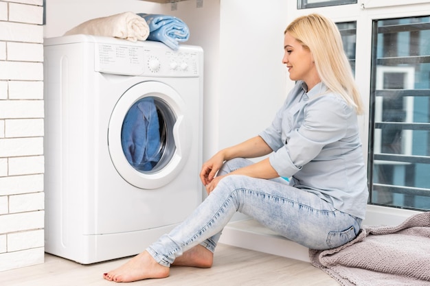 Een jonge huisvrouw met wasmachine en kleding. Wasdag.