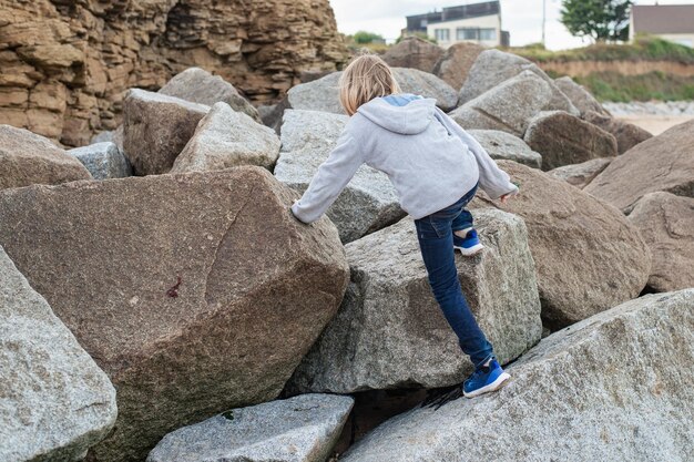 Een jonge jongen die op grote rotsen klimt