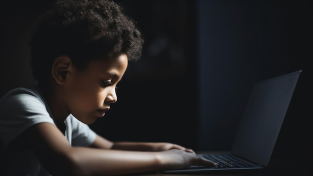 Een jonge jongen gebruikt een laptop in een donkere kamer.