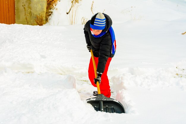 Een jonge jongen in het dorp maakt de sneeuw schoon en maakt een wandeling