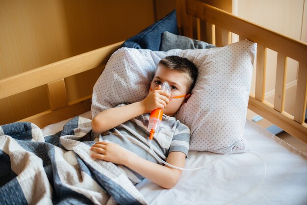 Een jonge jongen krijgt een inhalatie tijdens een longziekte. covid19, coronavirus, pandemie.