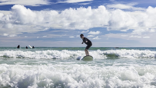 Foto een jonge jongen met een zwembril staat op een zacht bord terwijl hij aan het surfen is in een beginnersklasse