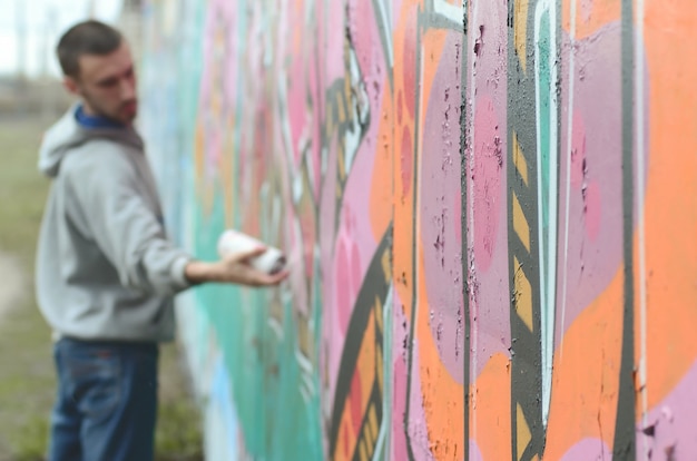 Een jonge kerel in een grijze hoodie schildert graffiti