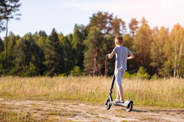 Een jonge kerel rijdt op een elektrische scooter op een onverharde weg in het bos