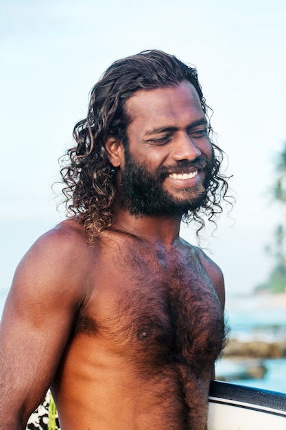 Een jonge knappe man met een donkere huidskleur en een surfplank