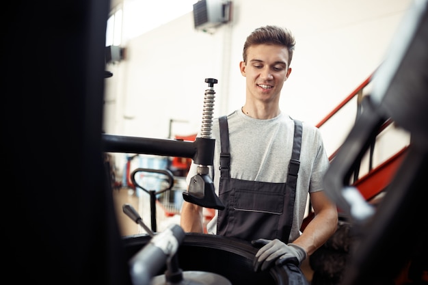 Een jonge lachende automonteur is aan het werk bij een autoservice en -onderhoud.