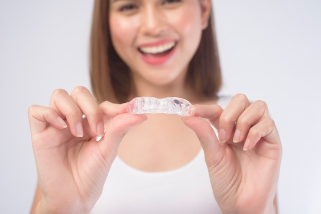 Een jonge lachende vrouw met invisalign beugels op wit, tandheelkundige gezondheidszorg en orthodontisch concept.