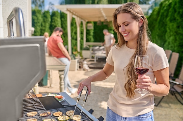 Een jonge langharige vrouw die zich dichtbij de barbecuegrill bevindt