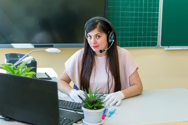 Een jonge lerarenvrouw met hoofdtelefoons en met microfoon