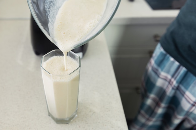 Foto een jonge man bereidt een smoothie van melk en vers fruit voor het ontbijt.