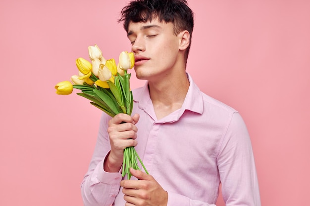 Een jonge man boeket gele bloemen romantiek poseren mode roze achtergrond ongewijzigd