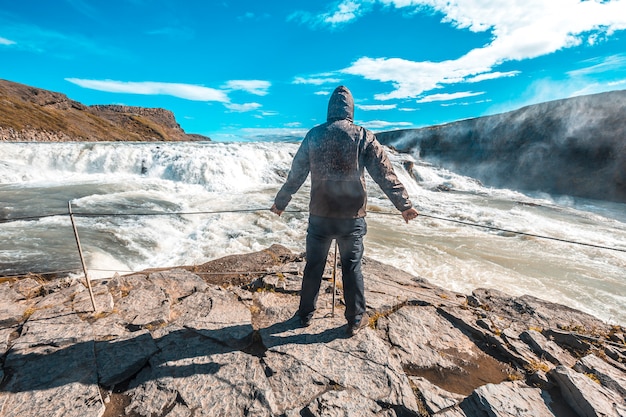 Een jonge man boven de Gullfoss-waterval in de gouden cirkel van het zuiden van IJsland
