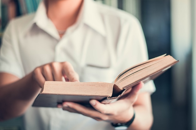 Een jonge man die er goed uitziet door boeken te lezen die op de vensterbank staan