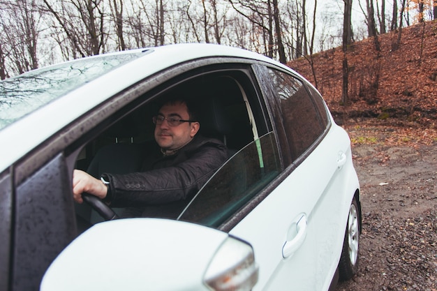 Foto een jonge man die in een auto rijdt op een regenachtige herfstdag