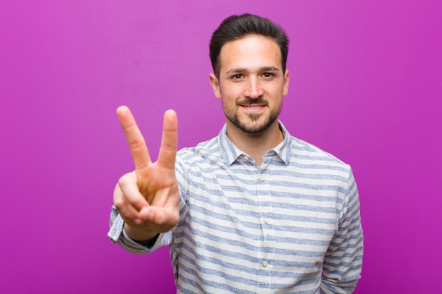 een jonge man die poseert terwijl hij met één hand overwinning of vrede gebaart