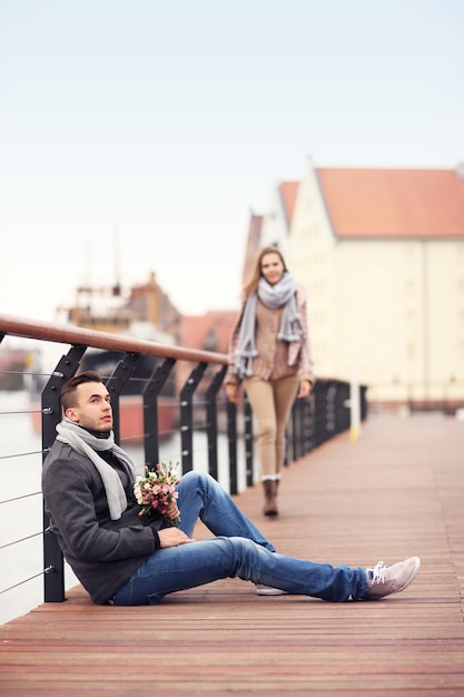 een jonge man die wacht op een vrouw met bloemen