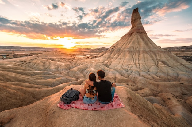 Een jonge man en een jonge vrouw kijken naar de zonsondergang bij Castildetierra in de woestijn van Bardenas Reales, Navarra, Baskenland.