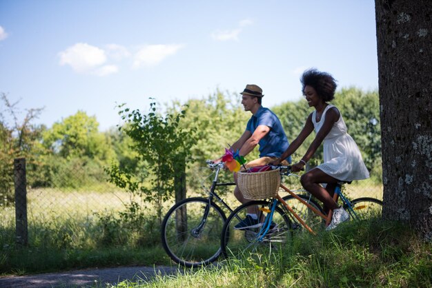 een jonge man en een mooi Afro-Amerikaans meisje genieten van een fietstocht in de natuur op een zonnige zomerdag
